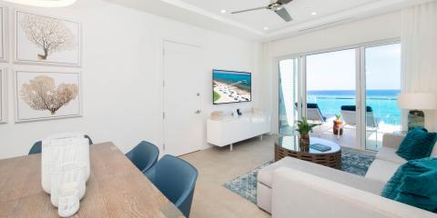 This image shows a modern, bright living room with a stunning ocean view
