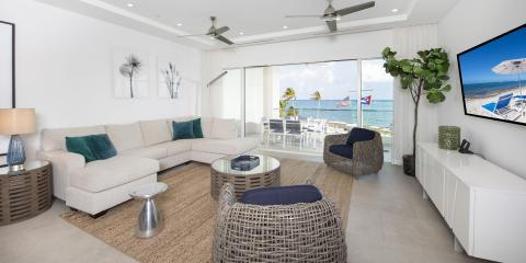 This image shows a spacious and modern living room with a scenic beachfront view