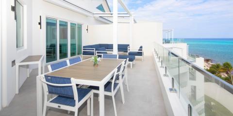 This image shows a stylish, modern rooftop terrace with a view of a clear blue ocean