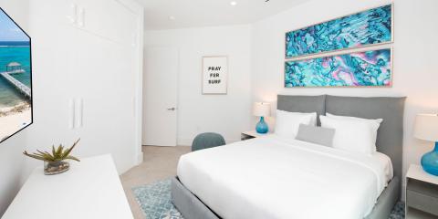 This image shows a modern and neatly decorated bedroom that has a refreshing ocean theme