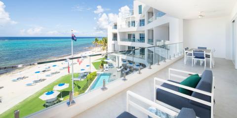 The image displays a modern beachfront resort or apartment complex featuring several amenities and a beautiful coastal view