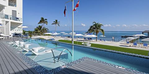 The image shows a luxurious outdoor setting featuring an infinity pool overlooking a serene beach