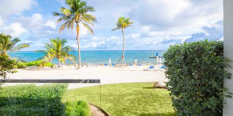 This image shows a beautiful tropical beach scene viewed from a vantage point between two white walls, possibly a gateway or an opened window