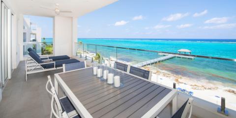 This image features a luxurious seaside balcony overlooking a stunning turquoise ocean