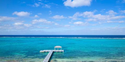 The image showcases a stunning view of a tropical seascape featuring a vibrant turquoise ocean with varying shades delineating different depths and coral areas