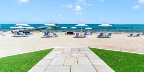 This image shows a serene beach scene with a sandy shore fronting a clear blue sea