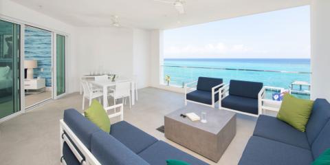 The image shows a well-decorated beachfront balcony with a panoramic view of a beautiful ocean