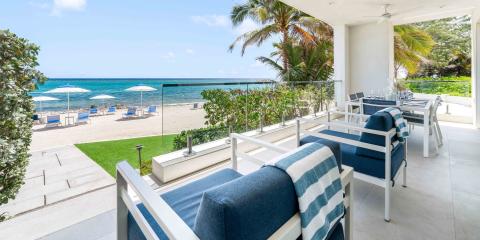 This image shows a beautiful outdoor patio dining area adjacent to a beach