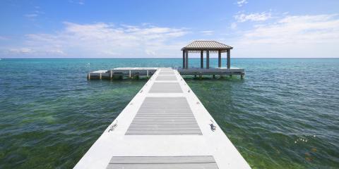 This image features a serene seascape with a long, narrow pier leading out to a small, covered gazebo over the water