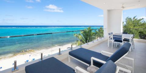 This image shows a beautiful beachfront balcony overlooking a clear blue sea