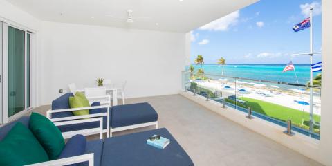 The image shows a spacious balcony overlooking a beautiful beach scene