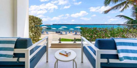 This image depicts a relaxing beachside outdoor setting viewed from a balcony