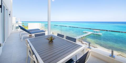 This image shows a beautiful oceanfront balcony with a view of a crystal-clear sea