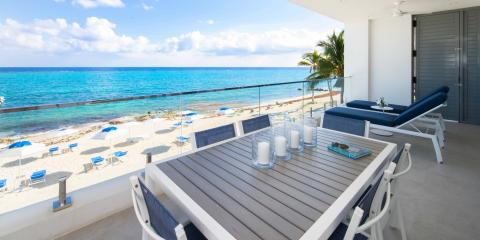 This image shows a serene oceanfront balcony setting overlooking a beautiful beach