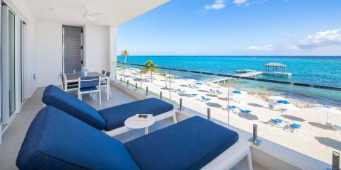 This image shows a luxurious beachfront balcony with a stunning view of the ocean