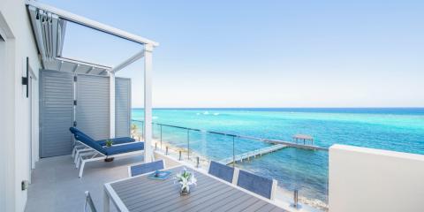 The image shows a beautiful seaside balcony with a stunning view of a crystal-clear ocean