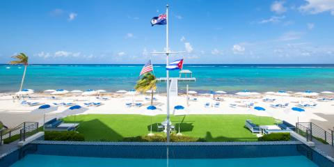 This image features a tranquil beachfront scene with a clear blue sky and crystal-clear turquoise waters