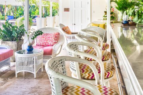 This image shows a bright and inviting tropical-style sunroom or porch