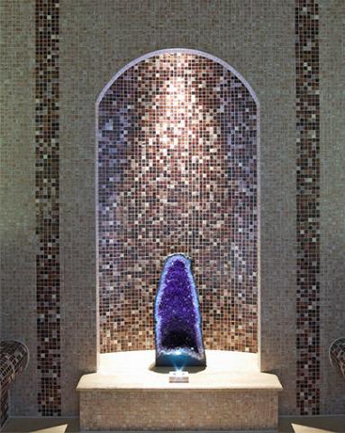 This image displays a large, striking geode placed on a pedestal within a niche