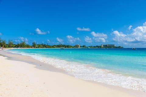 This image depicts a beautiful beach scene with clear turquoise waters and a pristine white sandy shore