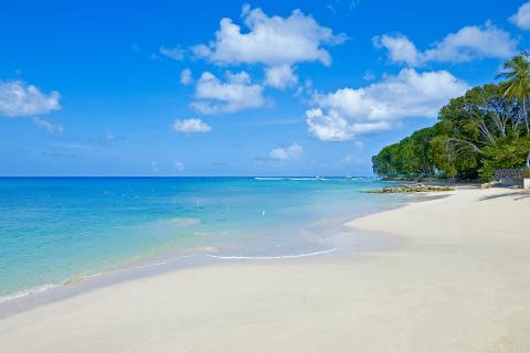 This image features a serene beach scene with clear blue sky and fluffy white clouds