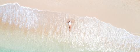 The image displays a serene beach scene captured from an aerial perspective