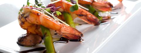 This image features a gourmet dish of large grilled shrimp, beautifully plated