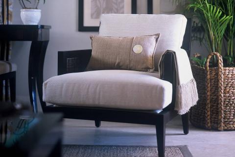 The image depicts a stylish interior setting featuring a sophisticated armchair with a beige upholstered cushion and a dark wooden frame