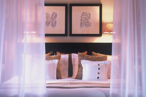 This image depicts a beautifully styled bedroom scene, viewed through semi-transparent white curtains