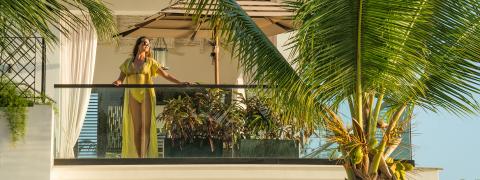 The image features a woman standing on a balcony