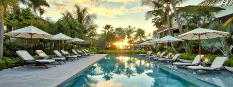 The image depicts a luxurious poolside scene at sunset