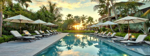 This image shows a luxurious outdoor pool area at sunset