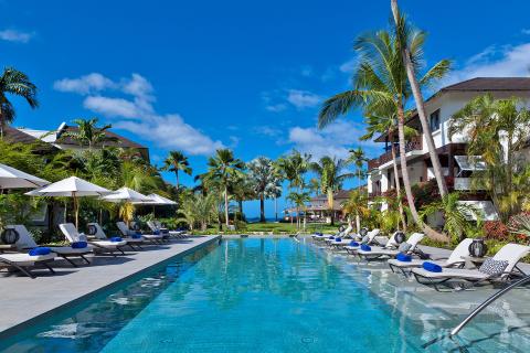 This image shows a luxurious outdoor swimming pool at a tropical resort or hotel
