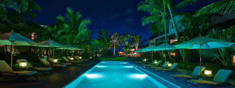 This image depicts a serene, nighttime view of a luxurious outdoor pool area
