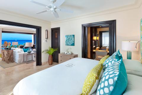 The image shows a luxurious and spacious bedroom with a fantastic ocean view