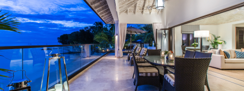 This image displays a luxurious and spacious indoor-outdoor living area during twilight