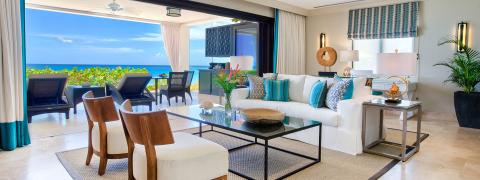 This image shows a luxuriously furnished living room with a spectacular ocean view