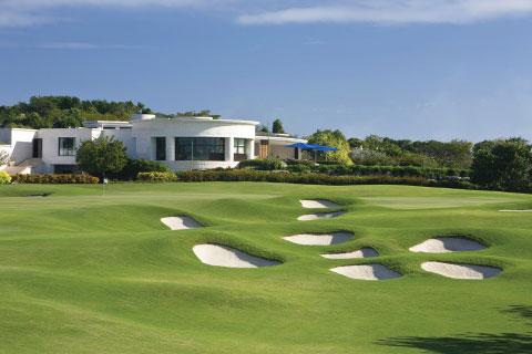 The image shows a lush golf course with several sand bunkers arranged in an eye-catching pattern
