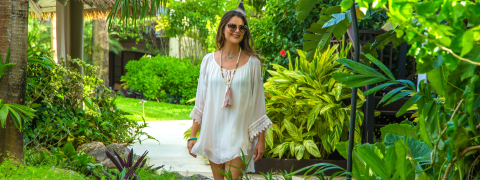 The image shows a woman walking along a lush garden path
