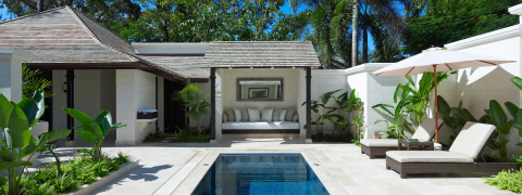 The image depicts a luxurious outdoor area featuring an inviting swimming pool with blue mosaic tiles