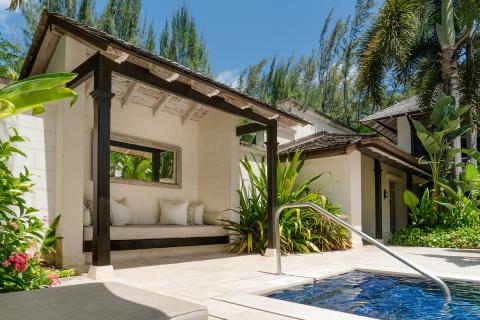This image shows a luxurious outdoor living space adjacent to a small swimming pool