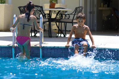 The image depicts two children at a swimming pool