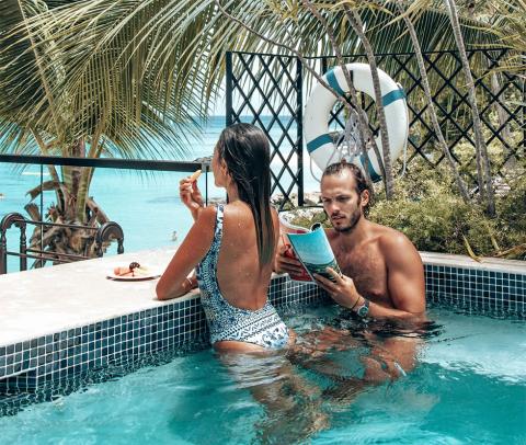 This image shows a man and a woman enjoying time together in a pool that overlooks a beach