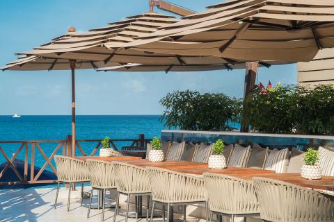This image depicts a picturesque outdoor dining area overlooking the ocean