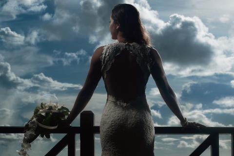 This image features a person dressed in an elegant lace wedding gown, viewed from the back