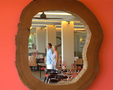 The image shows a view of a restaurant interior, seen through a large, circular, rugged-edged opening in a red wall