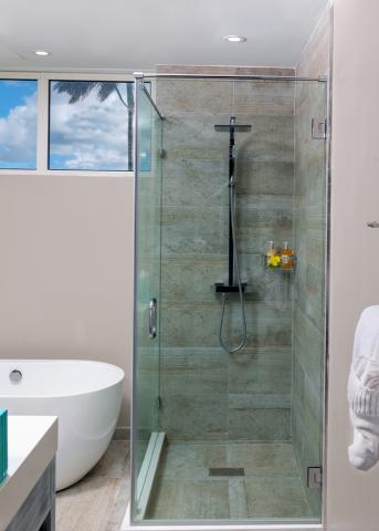 The image shows a modern bathroom with a clear glass shower enclosure