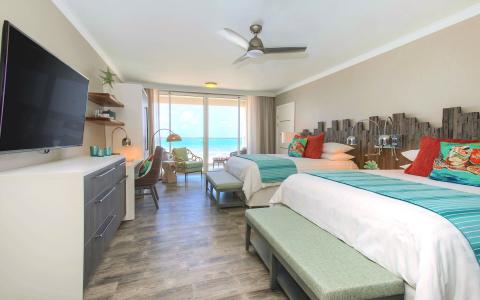 The image shows a bright and airy beachfront hotel room