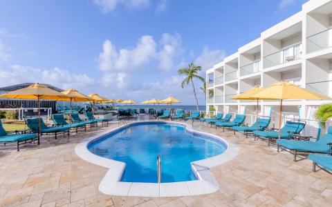 The image shows a luxurious hotel pool area on a sunny day