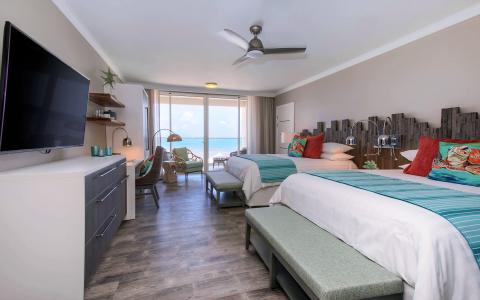 This image shows a neatly decorated hotel room with a beachfront view